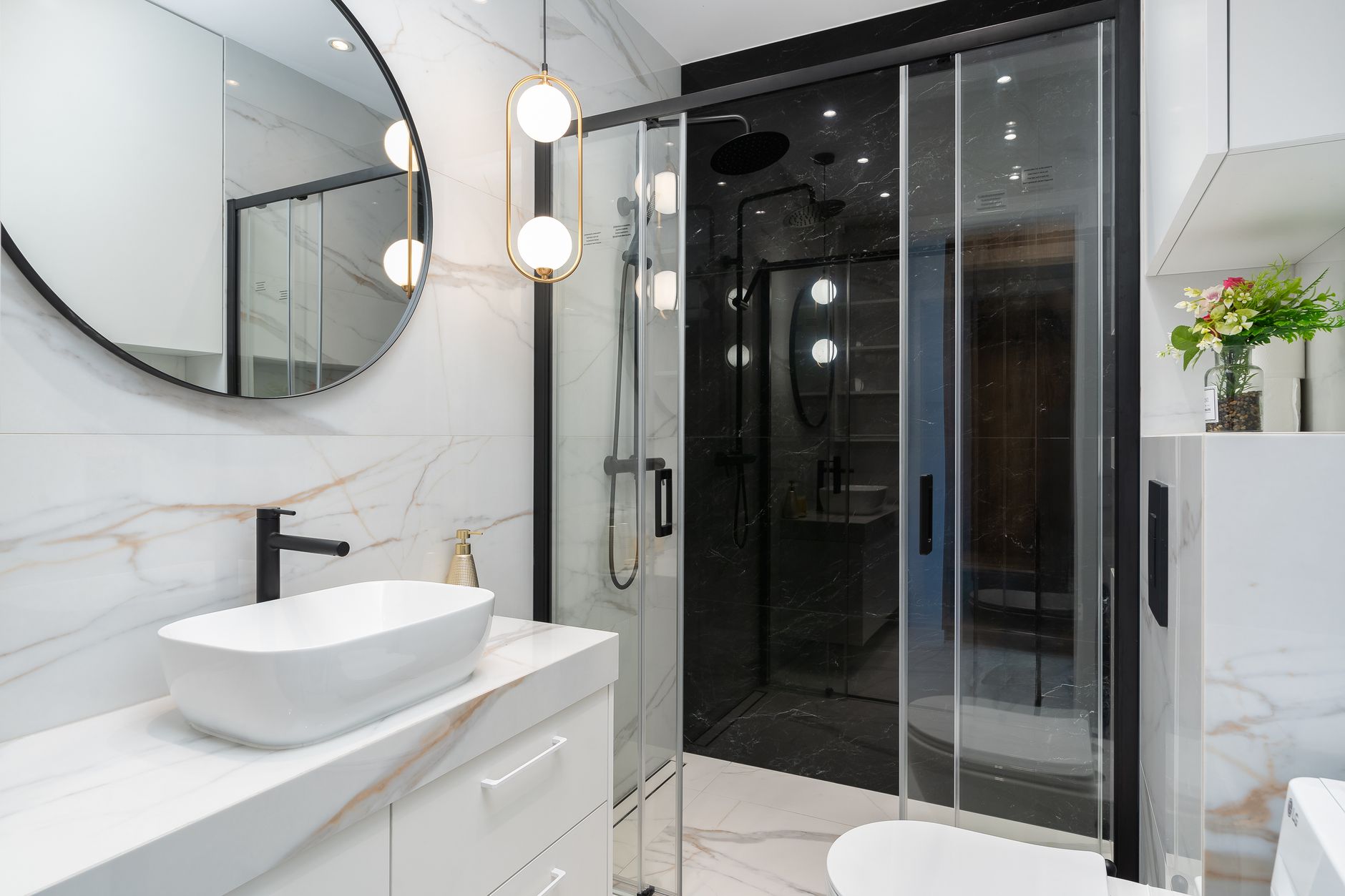 Sleek modern bathroom featuring a marble countertop, stylish circular mirror, and elegant lighting in Round Rock, TX